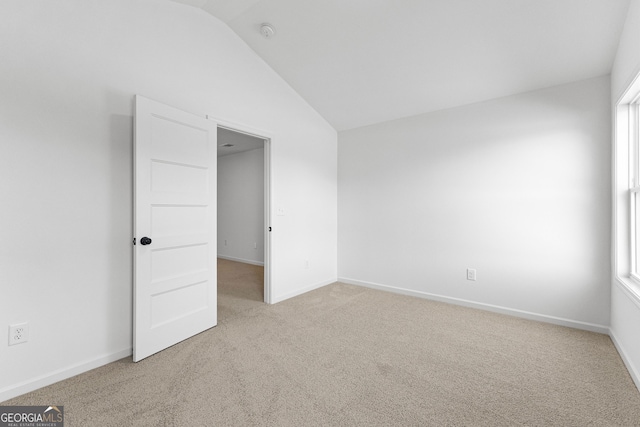 unfurnished bedroom with baseboards, carpet, lofted ceiling, and multiple windows