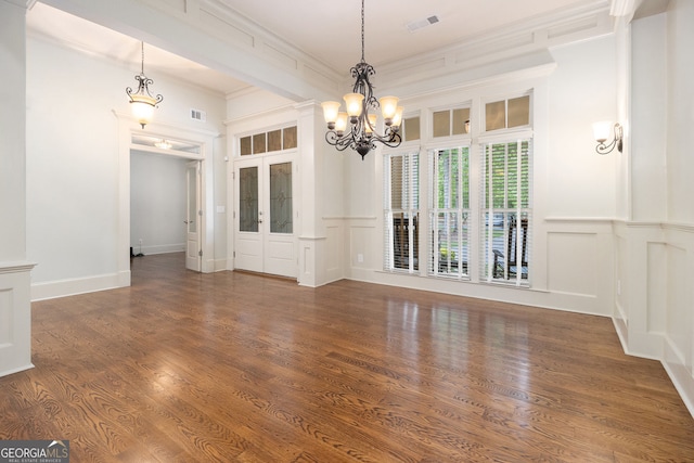 unfurnished dining area featuring a chandelier, ornamental molding, visible vents, and a decorative wall