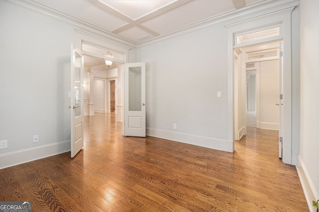 spare room with crown molding, baseboards, coffered ceiling, and wood finished floors