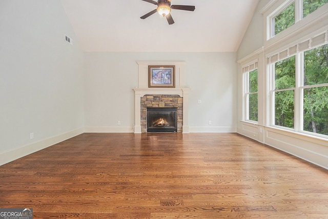 unfurnished living room featuring a stone fireplace, ceiling fan, a healthy amount of sunlight, and high vaulted ceiling
