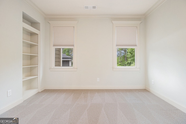 spare room with crown molding, visible vents, built in features, and carpet floors
