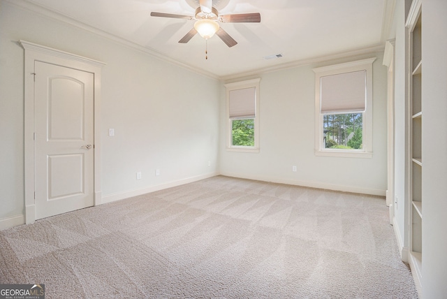 empty room with ceiling fan, light carpet, baseboards, visible vents, and ornamental molding