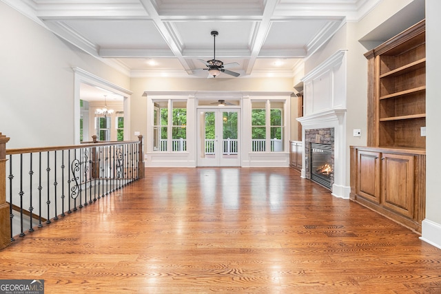 unfurnished living room with beamed ceiling, light wood-style floors, ceiling fan with notable chandelier, and a fireplace