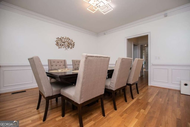 213 Shady Valley Dr, Carrollton, GA 30116 - dining area featuring crown molding, a decorative wall, light wood-style floors, and wainscoting