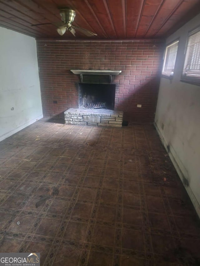 unfurnished living room featuring baseboards, a ceiling fan, wood ceiling, and a fireplace