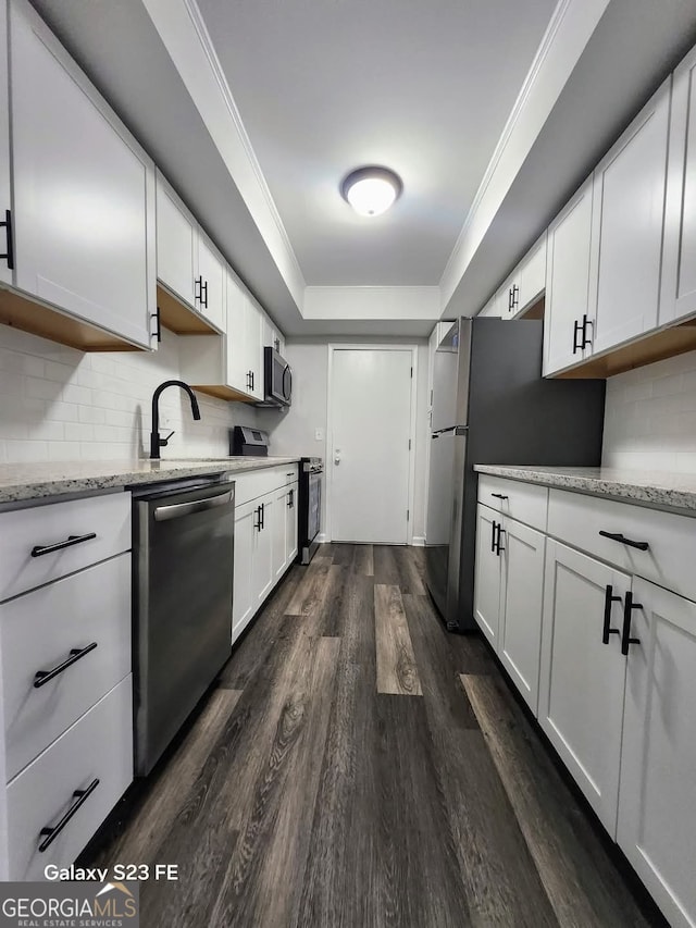kitchen featuring decorative backsplash, dark wood-style floors, white cabinetry, light stone counters, and appliances with stainless steel finishes