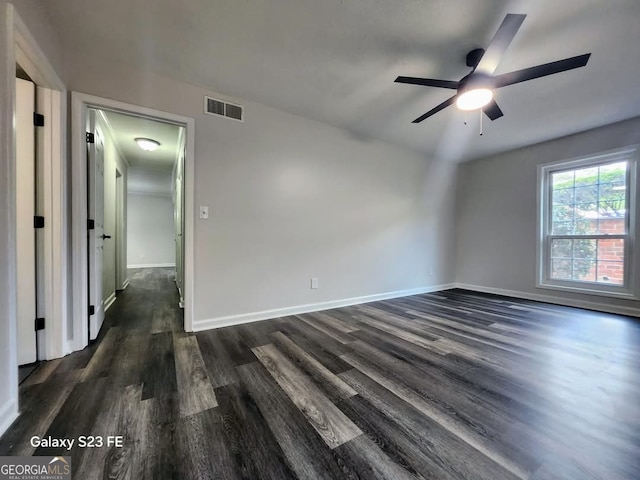 empty room with a ceiling fan, baseboards, visible vents, and dark wood-type flooring