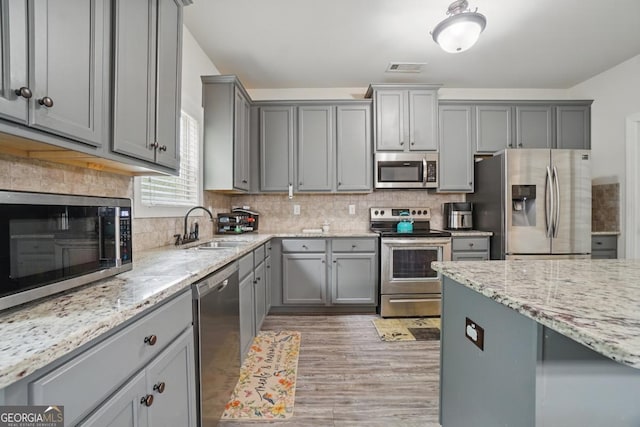 11028 Southwood Dr, Hampton, GA 30228 - kitchen with decorative backsplash, appliances with stainless steel finishes, light stone countertops, gray cabinetry, and a sink