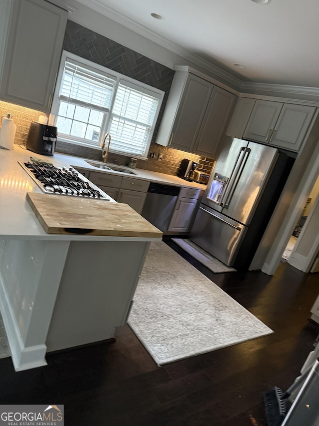 kitchen with a sink, stainless steel appliances, gray cabinets, a peninsula, and tasteful backsplash