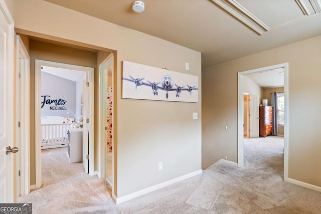hall featuring carpet floors, attic access, and baseboards