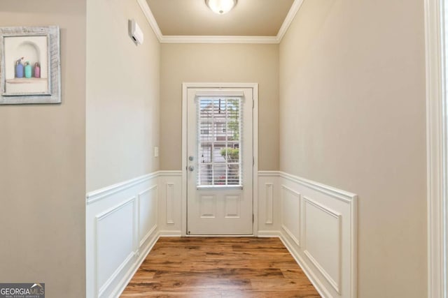 doorway featuring a wainscoted wall, ornamental molding, a decorative wall, and wood finished floors