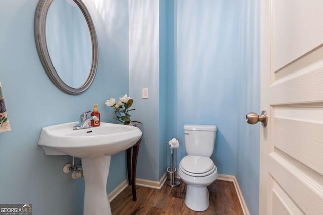 bathroom with baseboards, wood finished floors, and toilet