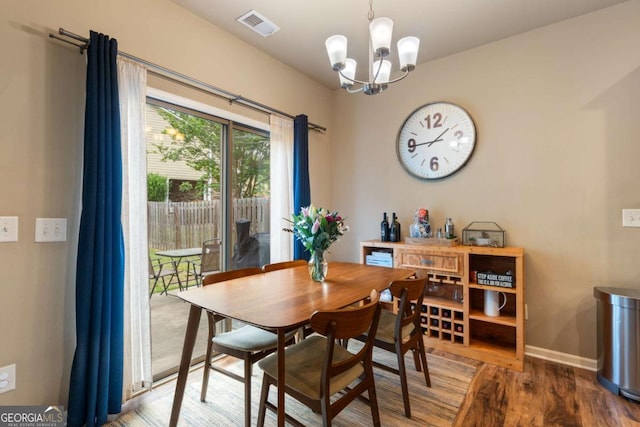 dining room with an inviting chandelier, baseboards, wood finished floors, and visible vents