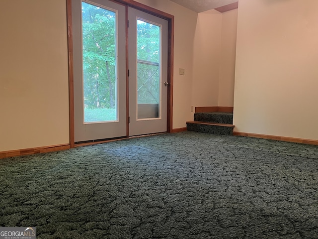 carpeted empty room featuring baseboards