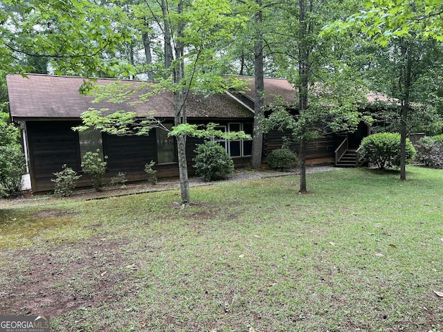 view of front of property featuring roof with shingles and a front lawn