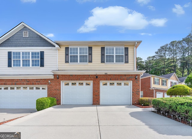 townhome / multi-family property featuring an attached garage, driveway, and brick siding