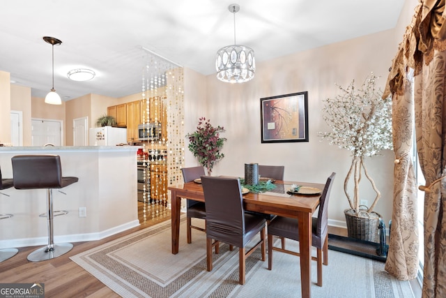 dining room with baseboards, an inviting chandelier, and light wood-style flooring