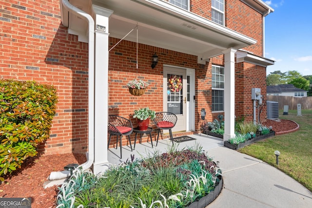 property entrance with a porch, brick siding, central AC, and fence