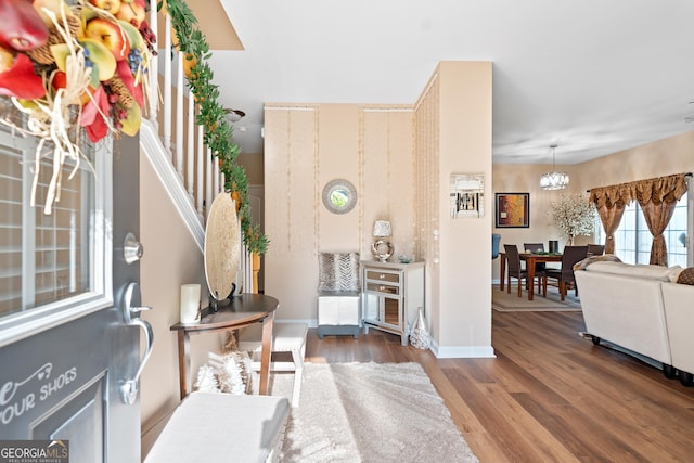 entrance foyer with baseboards, wood finished floors, and a chandelier