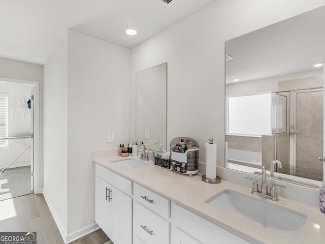 bathroom with a sink, a garden tub, a shower stall, and double vanity