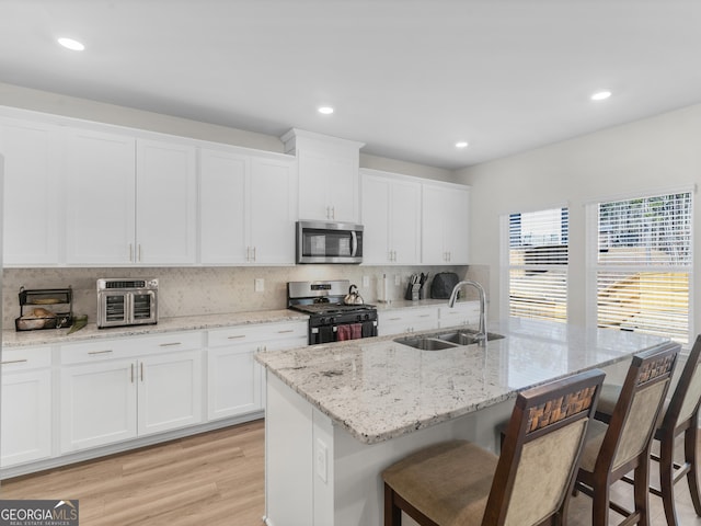 kitchen featuring a breakfast bar, gas range oven, stainless steel microwave, a sink, and backsplash