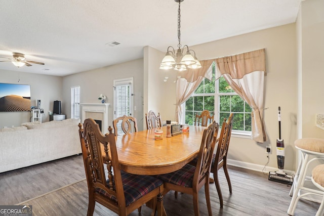 4015 Soaring Dr, Douglasville, GA 30135 - dining room featuring ceiling fan with notable chandelier, baseboards, wood finished floors, a tile fireplace, and visible vents
