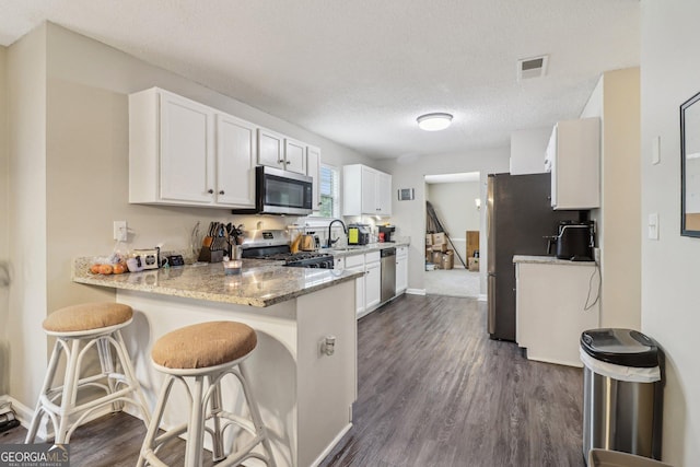 4015 Soaring Dr, Douglasville, GA 30135 - kitchen with visible vents, dark wood-style floors, white cabinets, a sink, and stainless steel appliances