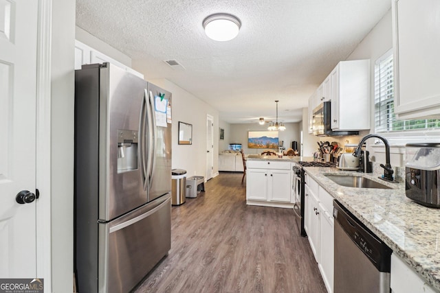 4015 Soaring Dr, Douglasville, GA 30135 - kitchen featuring a peninsula, white cabinets, a sink, dark wood finished floors, and appliances with stainless steel finishes