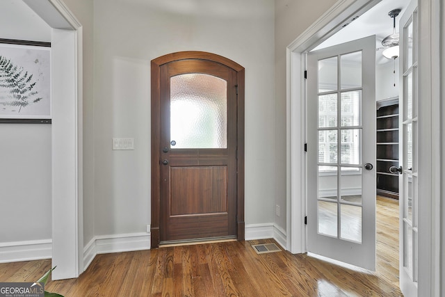 entrance foyer with baseboards, wood finished floors, and visible vents