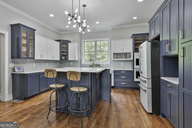 kitchen with freestanding refrigerator, glass insert cabinets, a breakfast bar area, recessed lighting, and light countertops