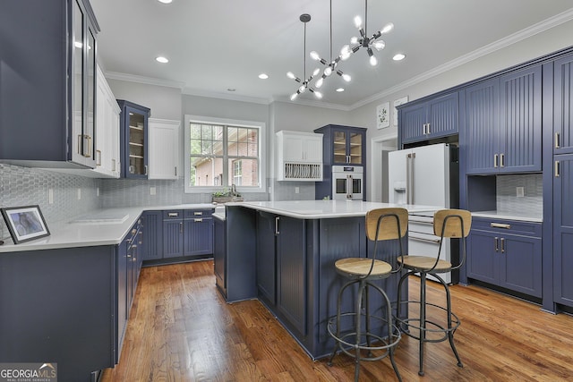 kitchen featuring a breakfast bar, glass insert cabinets, a center island, light countertops, and blue cabinetry