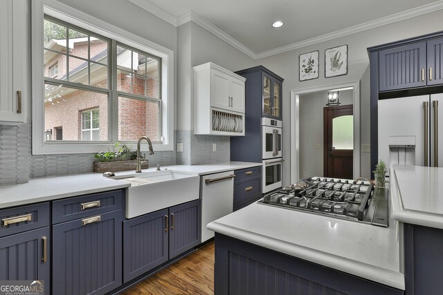 kitchen featuring white appliances, blue cabinetry, a sink, and tasteful backsplash