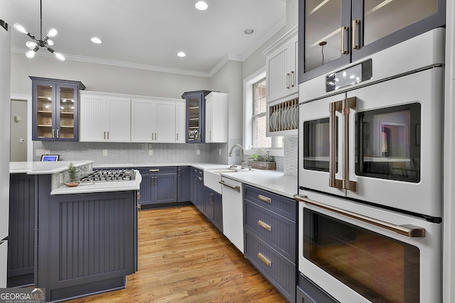 kitchen featuring ornamental molding, white appliances, light countertops, a sink, and backsplash