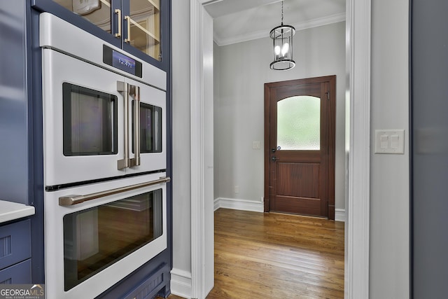entrance foyer with baseboards, ornamental molding, and wood finished floors