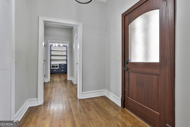 entryway with baseboards, an inviting chandelier, and wood finished floors