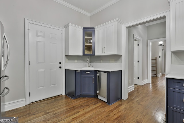 kitchen featuring light countertops, white cabinets, glass insert cabinets, and a sink