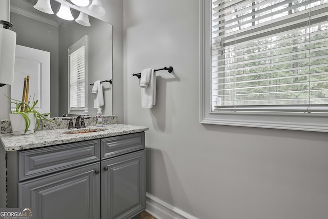 bathroom featuring baseboards, ornamental molding, and vanity