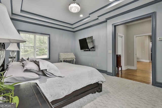bedroom featuring wood finished floors, baseboards, a raised ceiling, ornamental molding, and recessed lighting