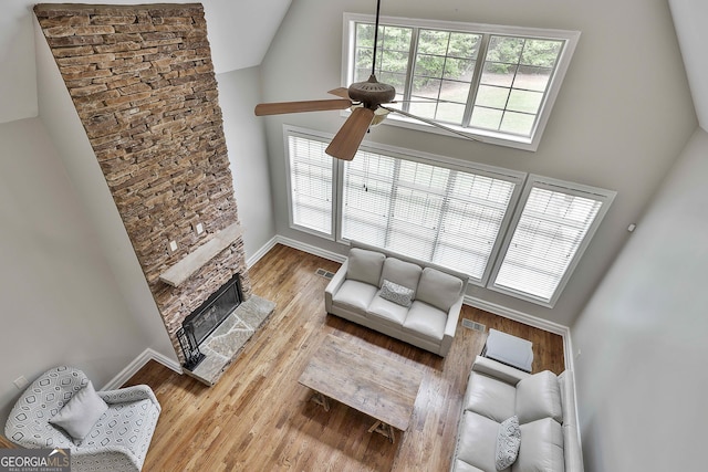 unfurnished living room featuring a ceiling fan, high vaulted ceiling, and a stone fireplace