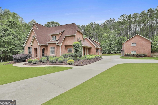 view of front of property with brick siding, driveway, and a front yard
