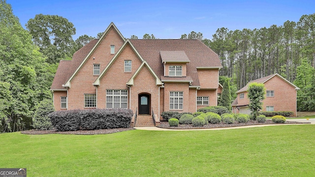 tudor home featuring brick siding and a front yard