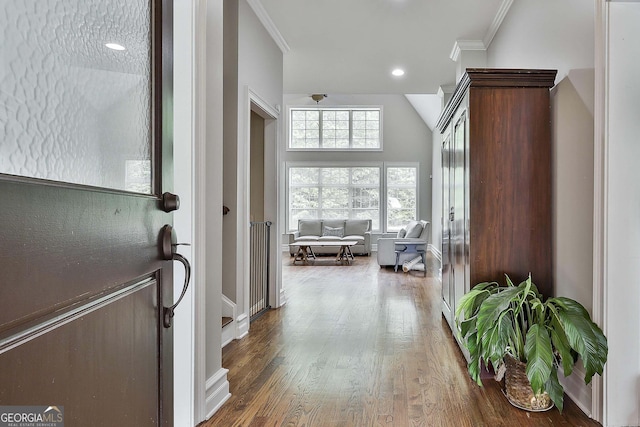 corridor with baseboards, ornamental molding, and wood finished floors