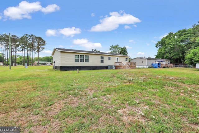 rear view of house with a lawn, central AC, and fence