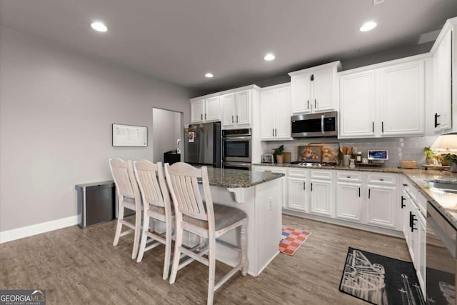 188 Lookout Way, Dallas, GA 30132 - kitchen with decorative backsplash, white cabinets, stainless steel appliances, and a kitchen bar