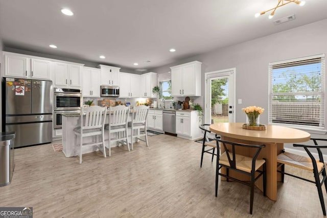 188 Lookout Way, Dallas, GA 30132 - kitchen with a breakfast bar area, light wood-style flooring, stainless steel appliances, white cabinetry, and visible vents