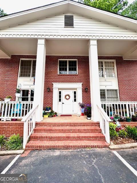 135 E Hill St Unit 12, Decatur, GA 30030 - view of exterior entry featuring covered porch, brick siding, and uncovered parking