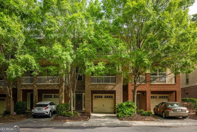 multi unit property featuring a garage, brick siding, and a balcony