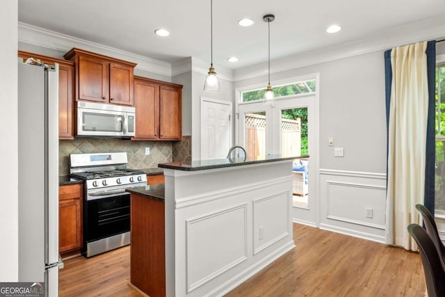 kitchen featuring brown cabinetry, backsplash, appliances with stainless steel finishes, light wood-style floors, and ornamental molding