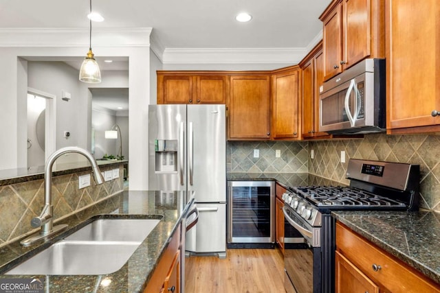 kitchen featuring hanging light fixtures, appliances with stainless steel finishes, a sink, light wood-type flooring, and wine cooler