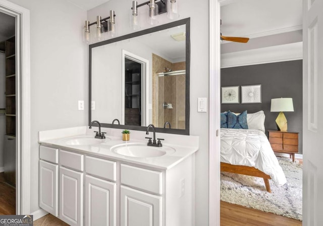 bathroom with connected bathroom, a shower stall, a sink, and wood finished floors